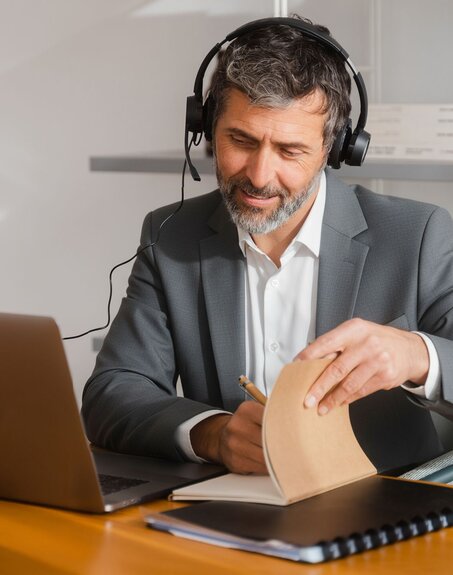 A gray-haired man works on his computer.