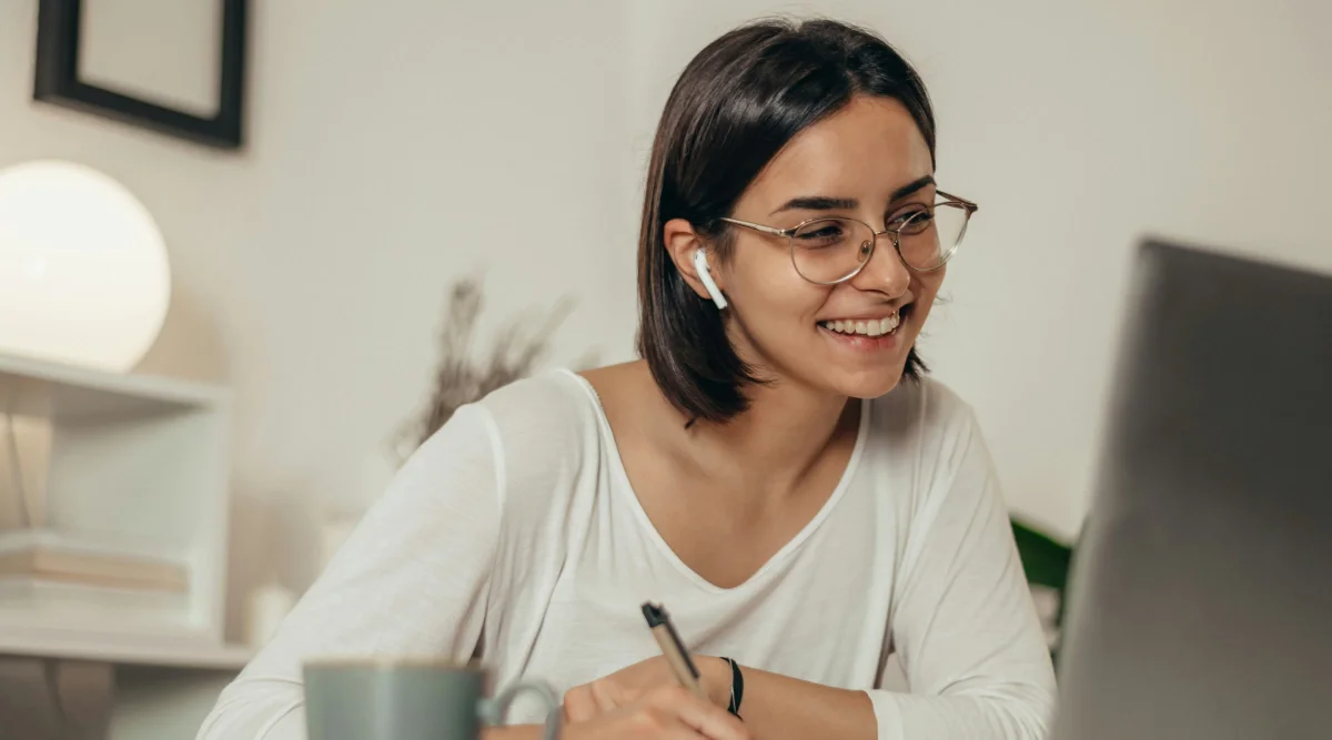 Woman with earbuds smiling at a laptop