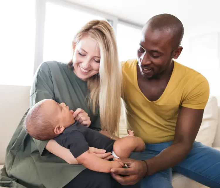 A family, where a smiling mother and father hold their baby.