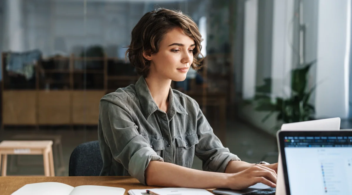 Woman typing on a laptop in a gray shirt