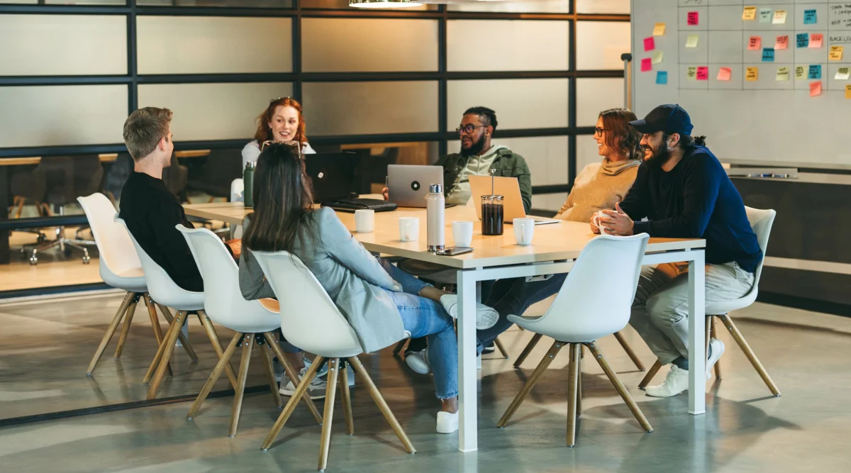 Group meeting around a table, laptops and notes visible