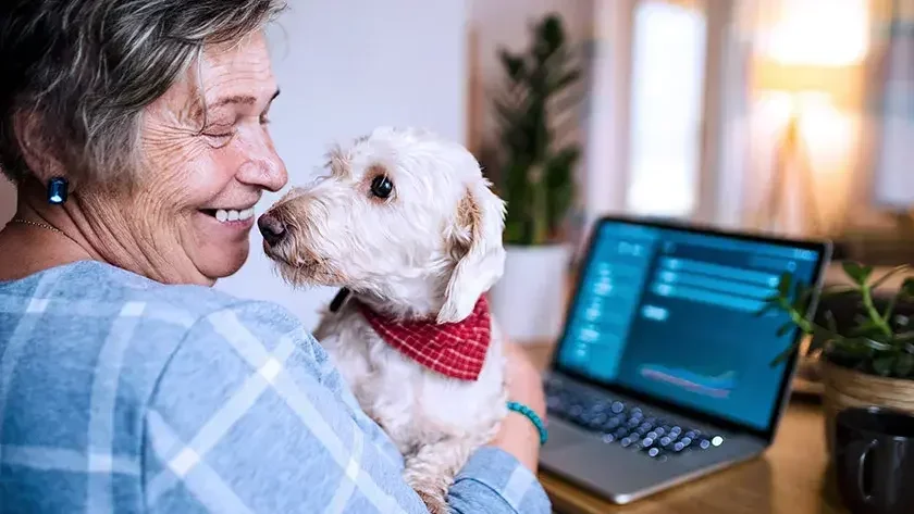 Senior woman holds dog in lap at home.