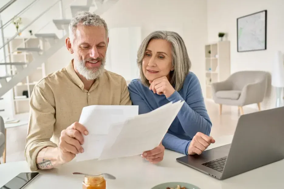 An elderly couple seated in a cozy living room, thoughtfully discussing the key differences between a living will and a last will and testament before deciding to create one for their estate planning.