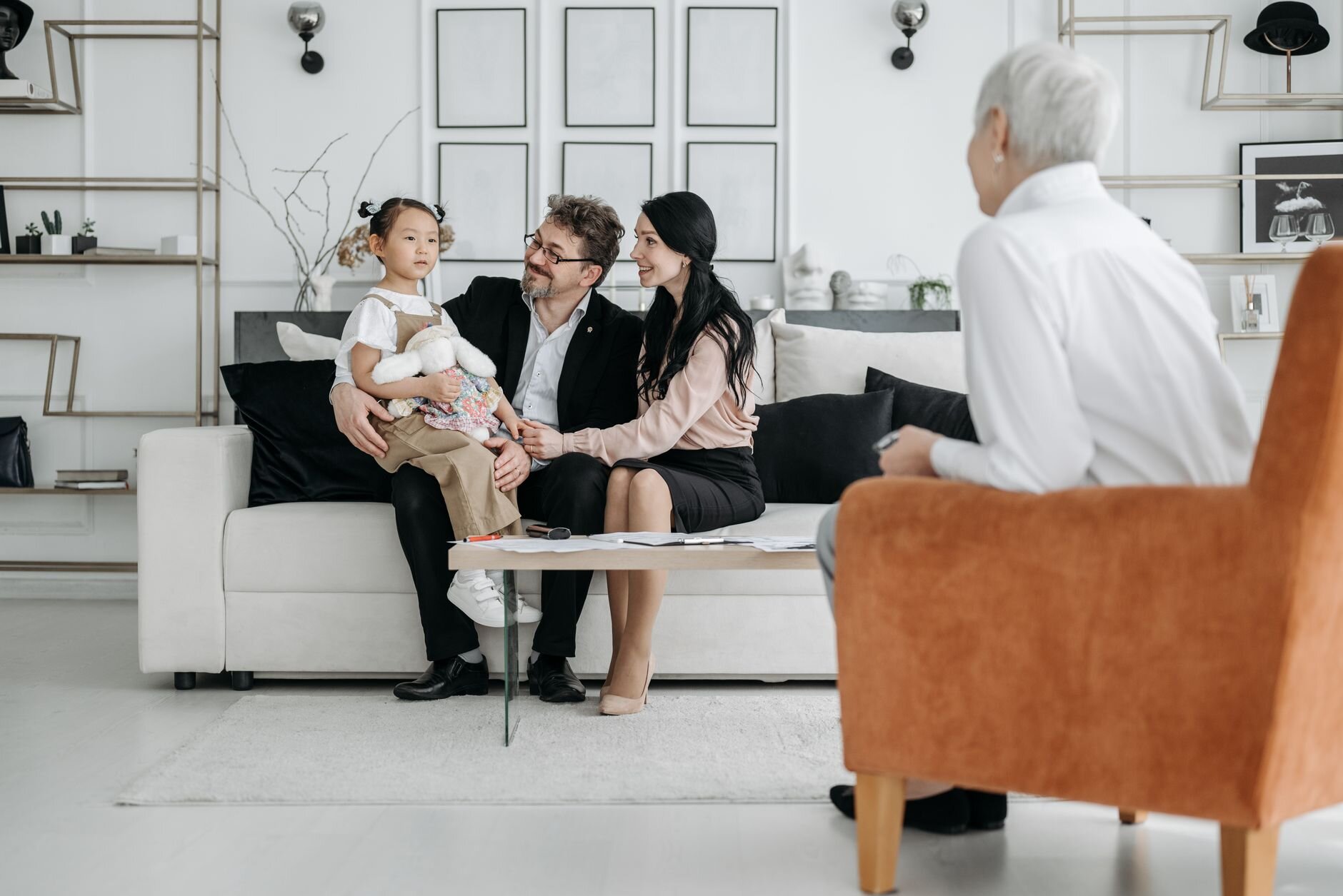 Three adults and a young girl sitting together on a couch while reviewing paperwork.