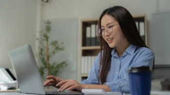 Woman typing on a laptop in a well-lit office space