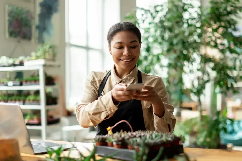 A plant shop owner takes pictures of plants for her social media account.