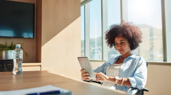 Woman using tablet in sunny office