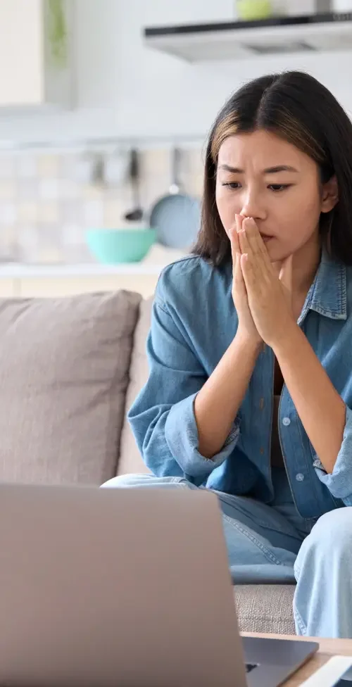 A woman sitting on a couch researching attorneys that can create an independent contractor agreement