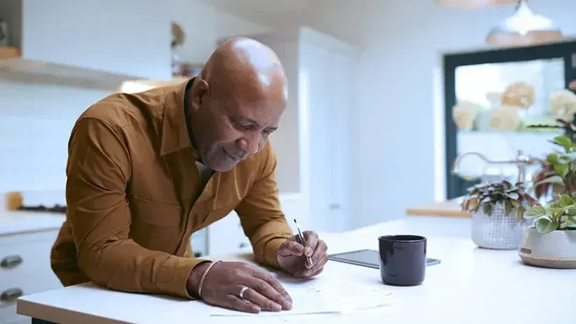 Man filling out estate planning forms at the kitchen counter.