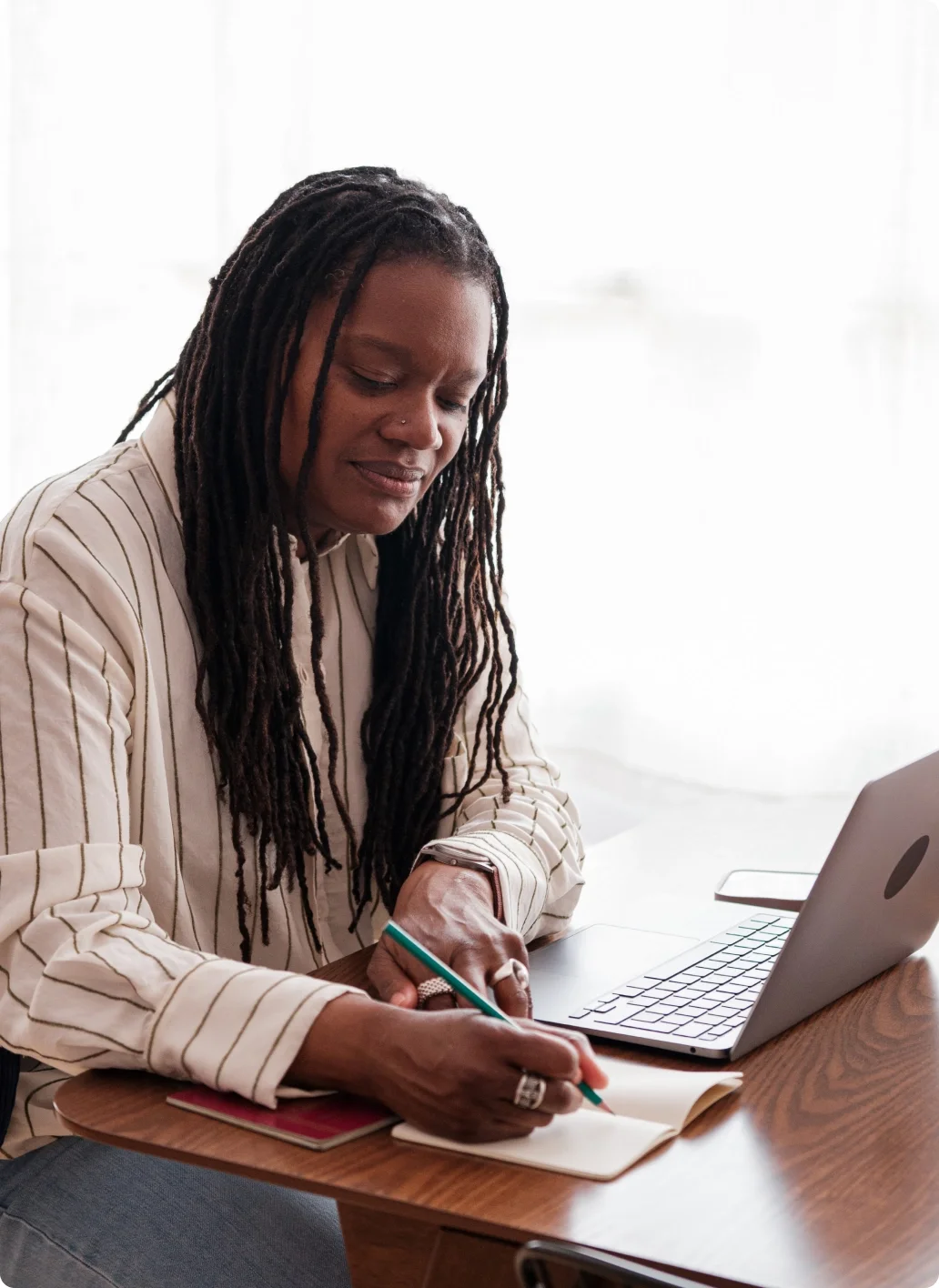 A woman in front of the desk writing in the notebook