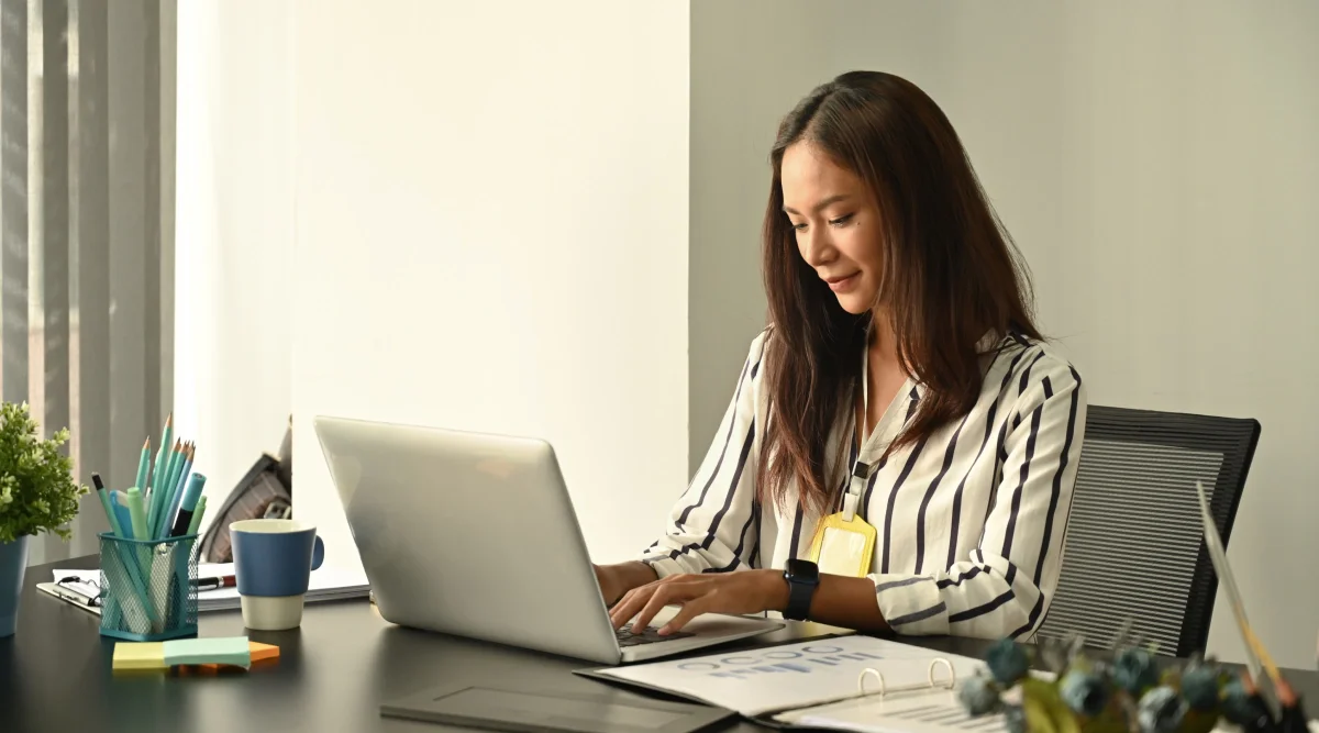 Woman in a striped shirt using a laptop at a desk