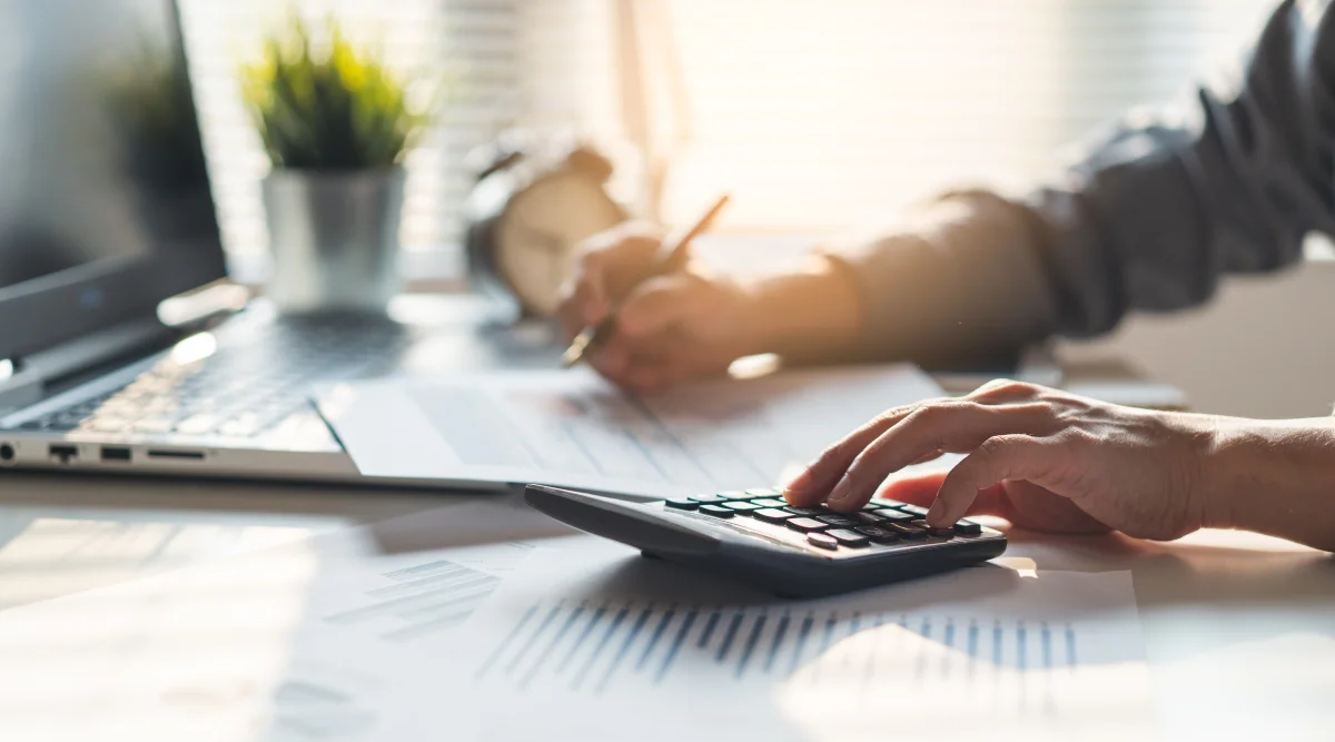 A man uses a calculator on an aesthetic desk at golden hour  