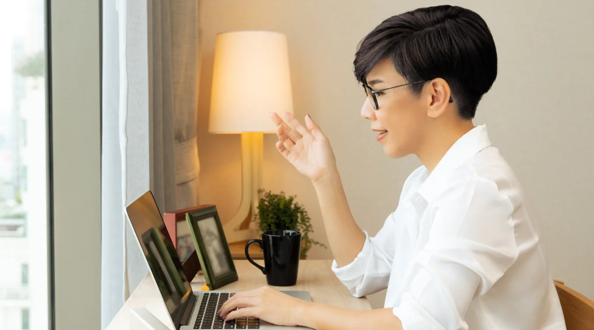 Woman in white shirt video chatting on laptop