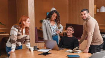 Four colleagues discussing work around a laptop