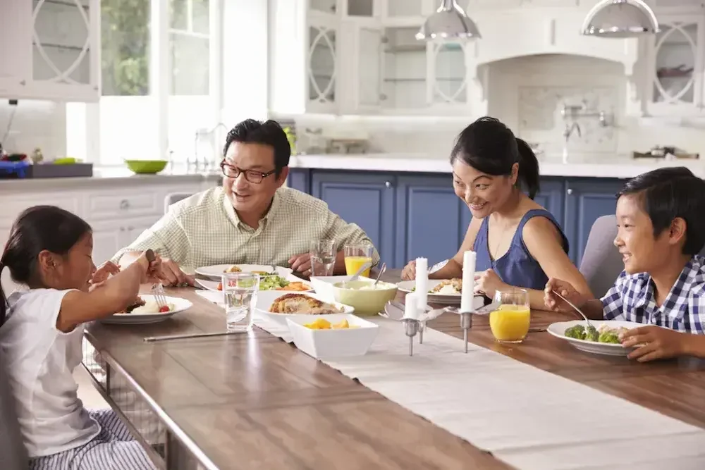 A family of four having breakfast in the kitchen on a dining table.