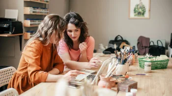 Two women collaborating on art projects at a table