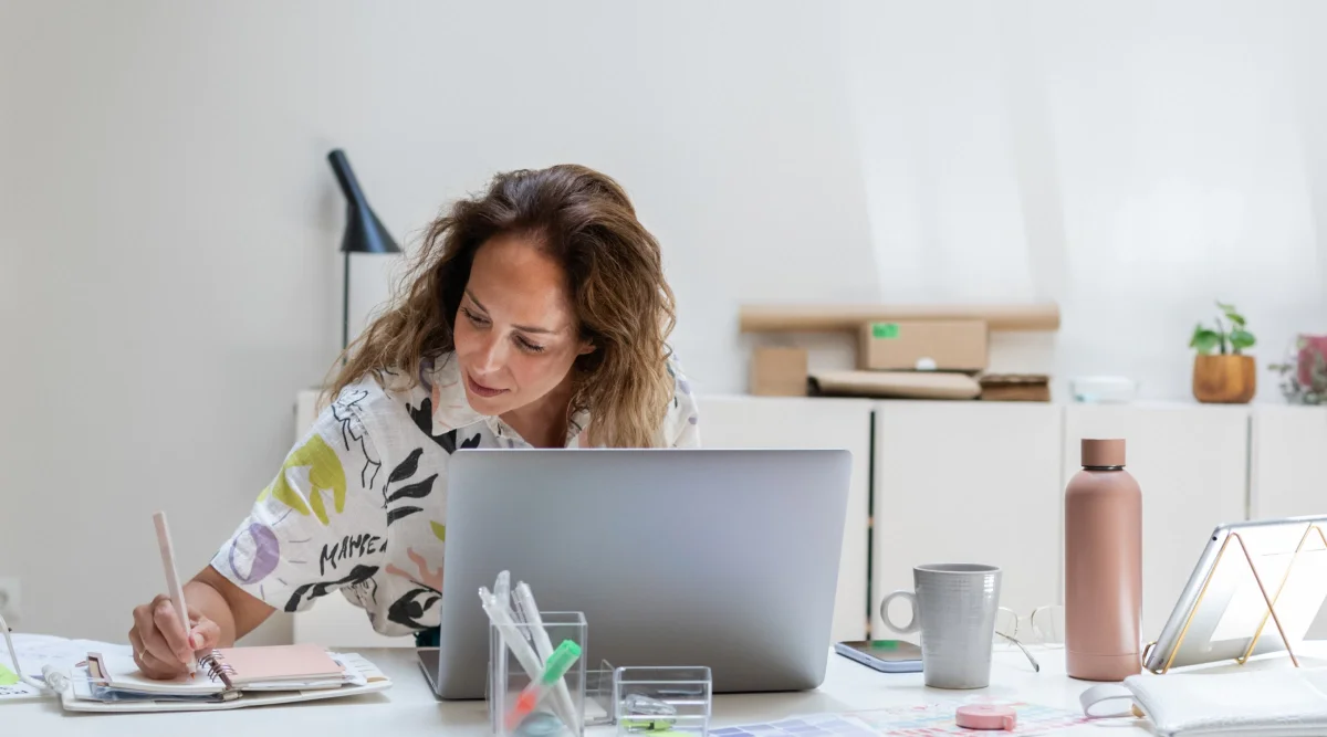 A woman sits in a cafe and talks on phone about how to file a DBA in Arizona.