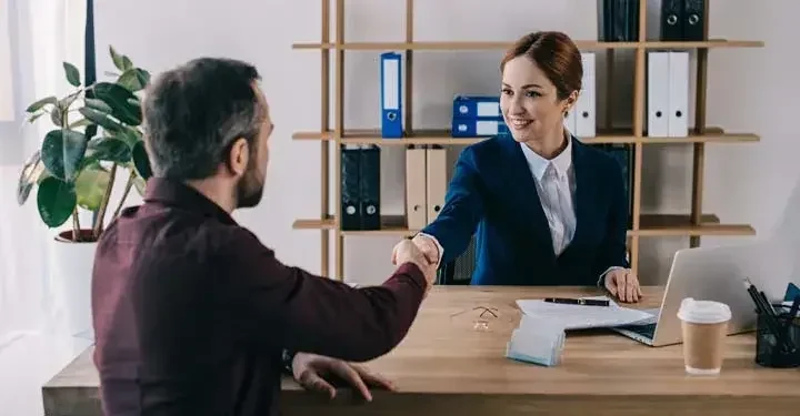 A trademark attorney shakes the hand of her client after a meeting.