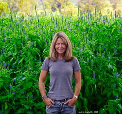 Mamma Chia founder Janie Hoffman standing in a field of tall chia plants with small purple flowers.