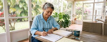 A woman reviews paperwork at her desk.