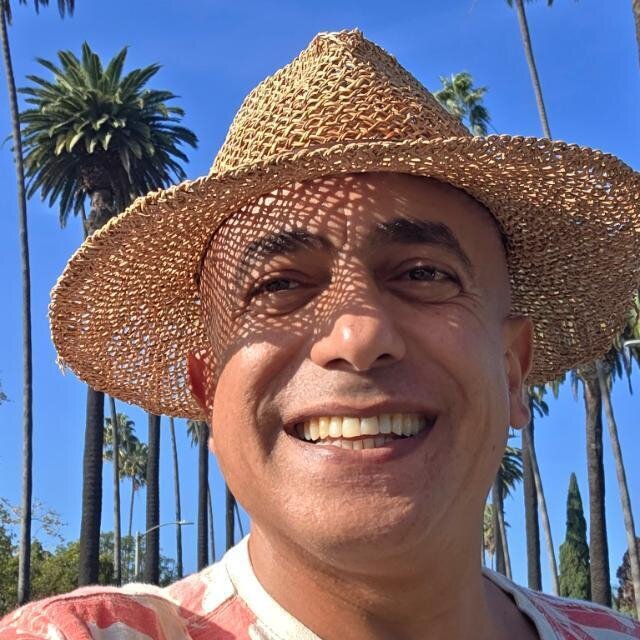 Selfie of Ahmed Radwan smiling widely in a straw hat. Behind him is Hollywood Boulevard lined with palm trees against a clear blue sky.