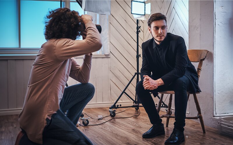 An image of a male model posing for a photographer in the studio. 