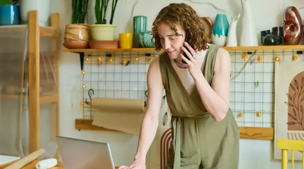 The owner of a Virginia LLC talks on the phone with a customer while looking up an order on her computer.