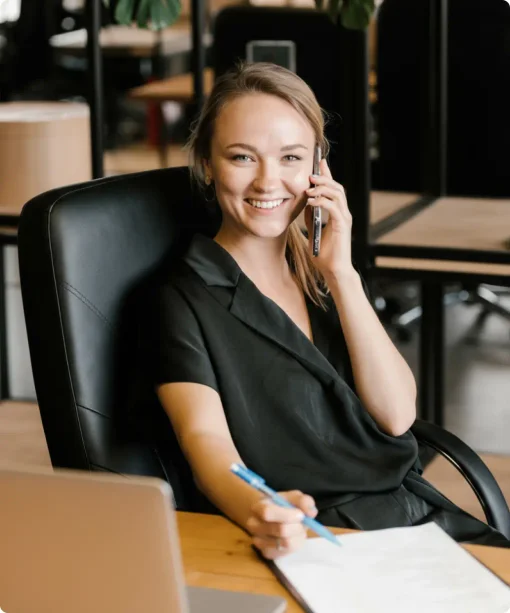 A woman with blond hair sits at her desk and answers calls 