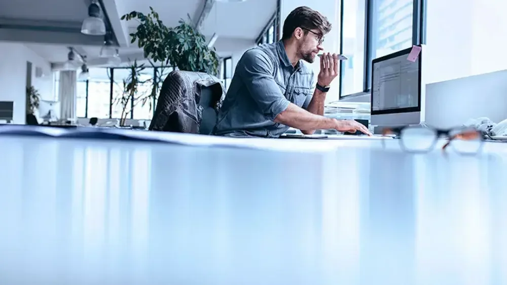 A business owner is looking at the laptop while talking on the phone 