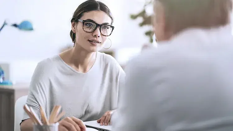 A woman consults a client in the office regarding opening an estate account.