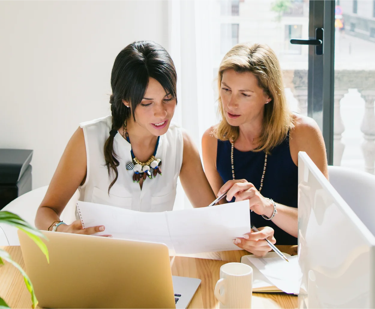 Two women discuss a project in a modern office