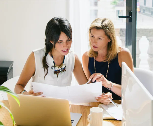 Two women discuss a project in a modern office