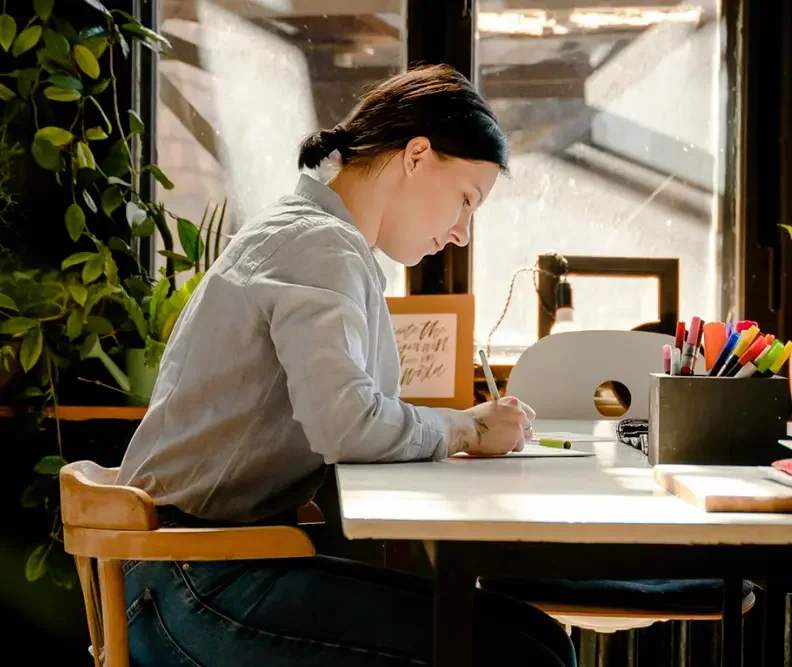 Woman writes at her desk