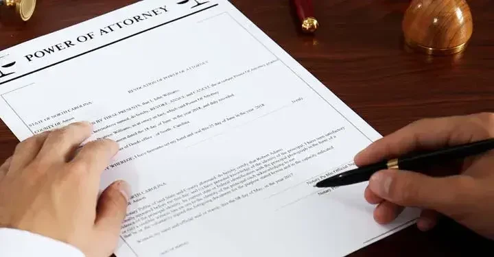 Man signing a power of attorney document with a ballpoint pen.