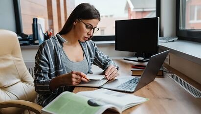 A professional woman staring at a document in front of a computer screen