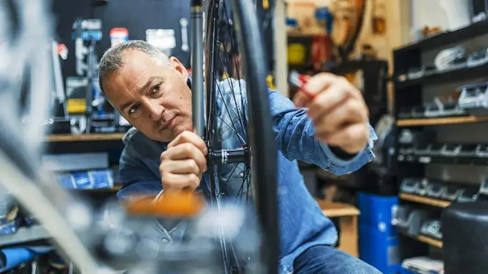 A man fixes a bicycle tire in his shop.