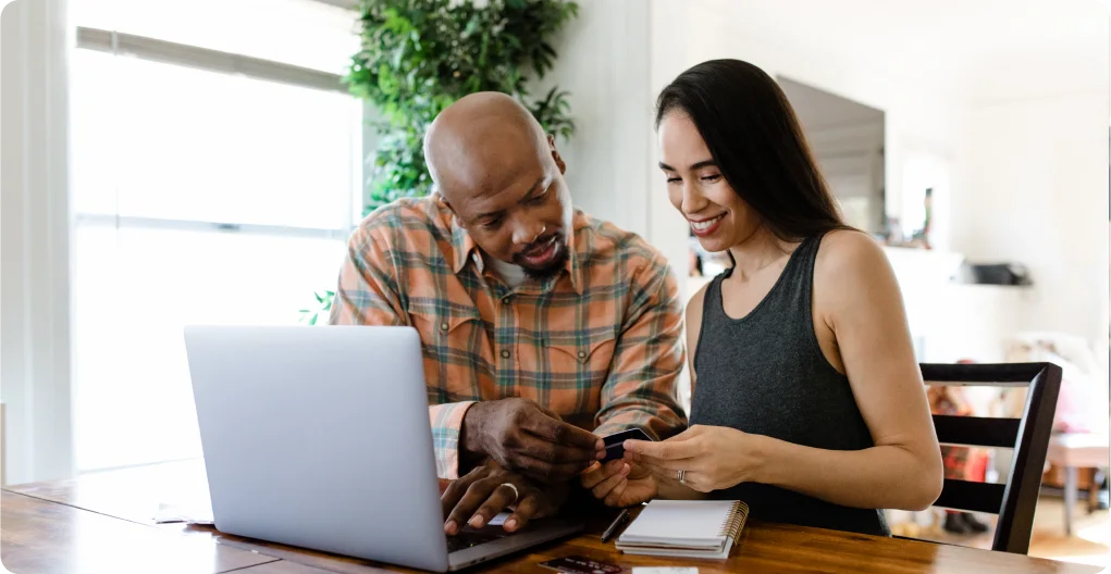 A man and woman browse their computer in their modern home.