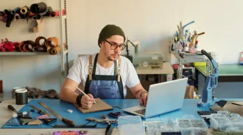 Artisan working on crafts, laptop open on table