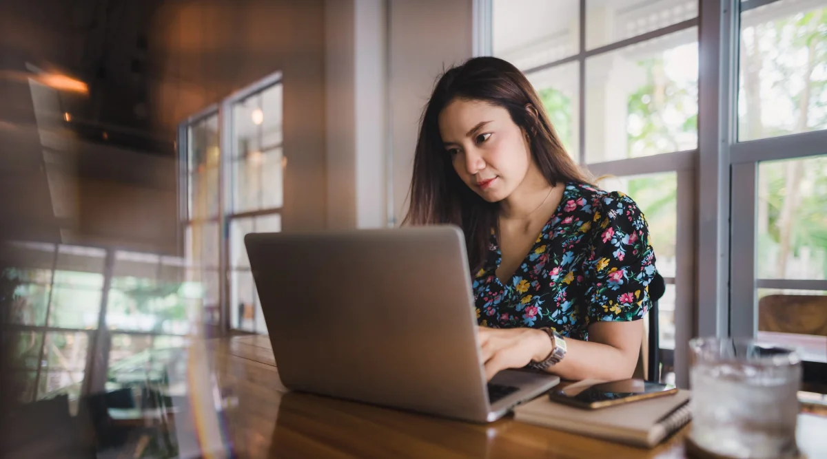 Woman focused on laptop in cafe setting