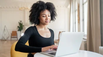 Woman smiling while using laptop in bright room