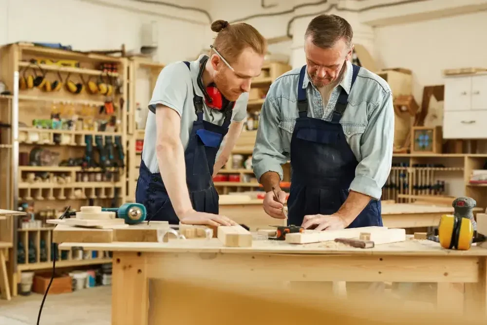 Two business partners stand at a workbench in their carpentry shop.