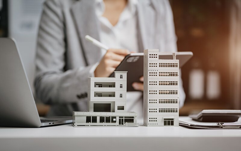 An image showing a miniature building created using blocks with an agent holding a tab in the background.