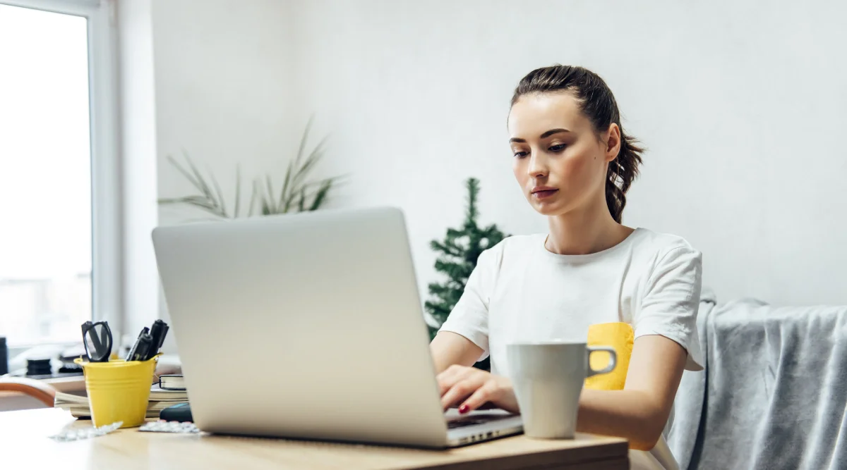 Woman typing on laptop with a coffee nearby