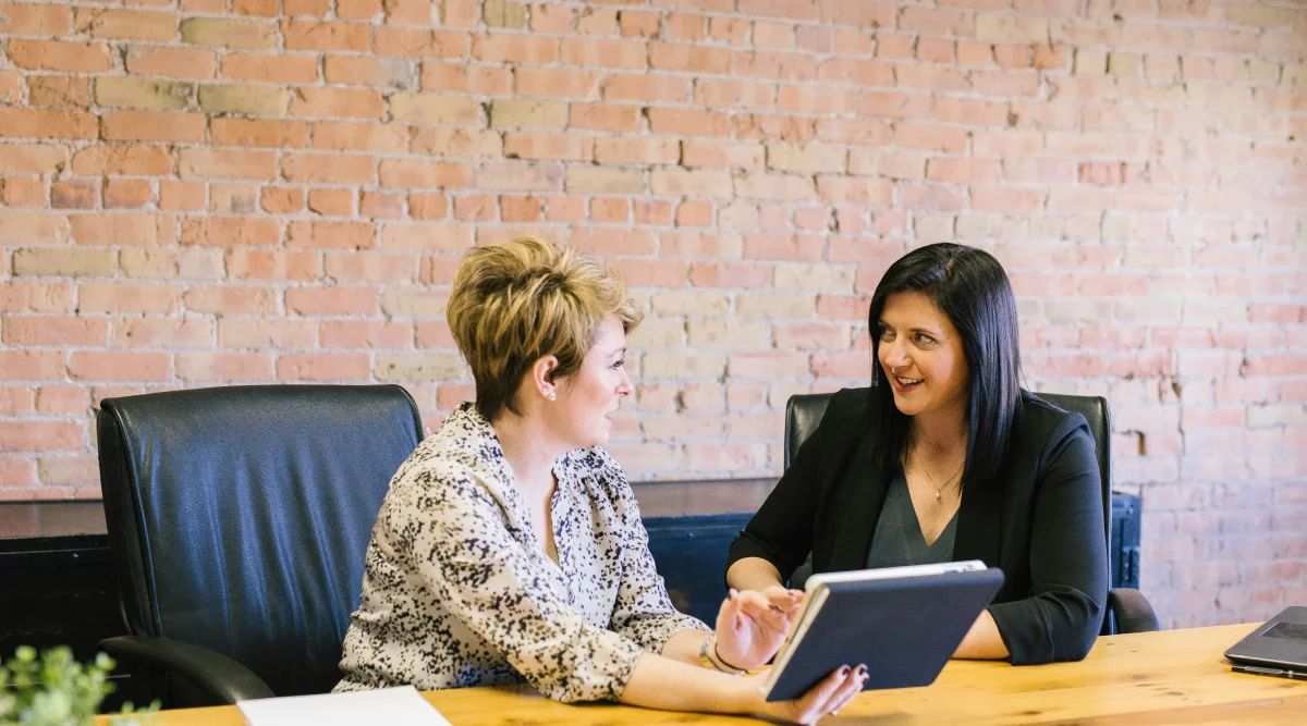 Two women having a discussion with a tablet in an office