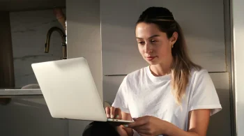 Woman in white shirt working on a laptop