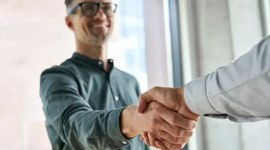 A man smiling and shaking hands with another man after choosing LegalZoom's estate planning services.