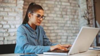 Woman in glasses working on a laptop in a cozy space