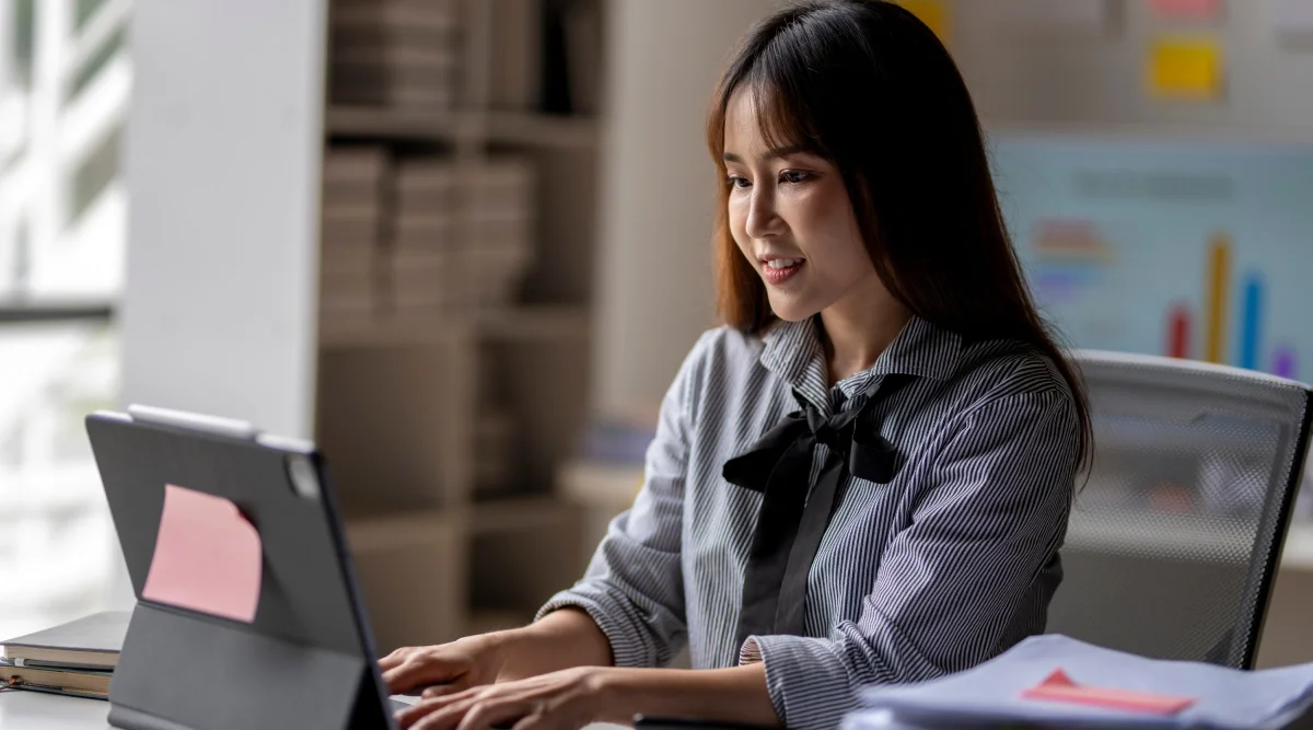 Woman in striped shirt working on a laptop with a smile