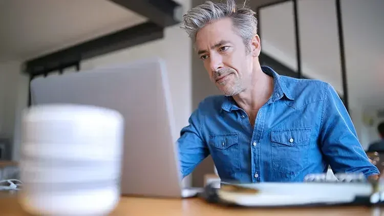 A serious-looking man working on a laptop, learning how to set up a trust.