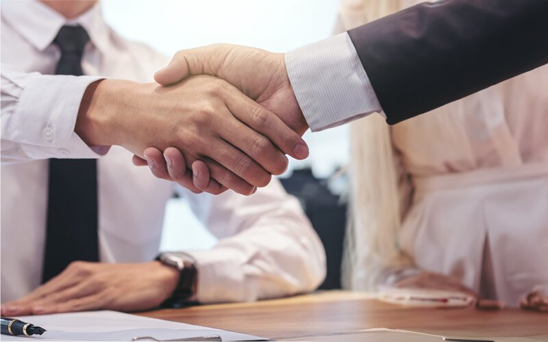 An image of two people shaking hands at a meeting.